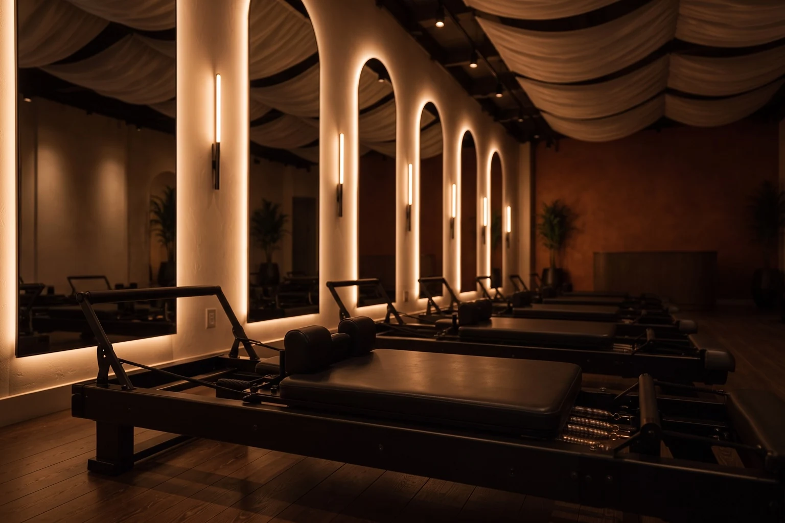 Concept visual: a single reformer bed up close, springs and frame warmly lit beneath backlit arched mirrors